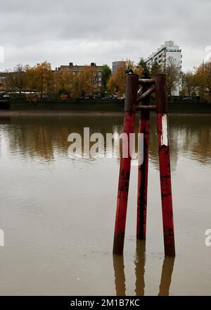 Old remains of bridge structure protruding up from and reflected on the River Thames London next to grovsenor railway bridge Stock Photo