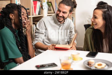 Multiethnic students sitting at coffee bar reading books  and having fun together. Stock Photo