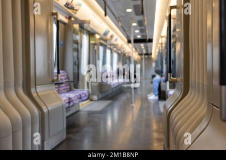 Blurred empty interior of a modern metro train, inside of an underground subway train with two unrecognizable people. Public transportation concept. Stock Photo