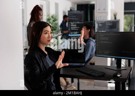 Serious system engineer working with hologram and coding language in programming software company. Analyzing holographic html script and augmented reality to develop new server interface. Stock Photo