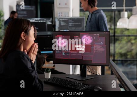 Shocked programmer typing html code encountering hacking alert on computer, dealing with unexpected system error and message flashing on monitor. Cyber security development office. Stock Photo