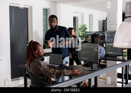 Team of programmers typing machine learning app code on programming computer, sitting at desk in big data office. Web developers working on database system with html script in it security agency. Stock Photo