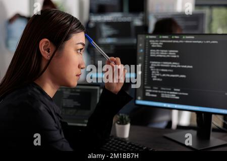 Pensive asian it programmer thinking at html script development, brainstorming ideas to create html code. It software developer working at database server in software office company Stock Photo