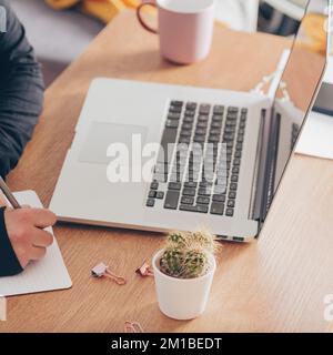 Top view of businesswoman at her workspace. Desk with laptop, diary and coffee cup. Stock Photo
