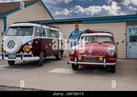 Young man standing by vintage classic VW Camper Van parked on Seafront Promenade Stock Photo