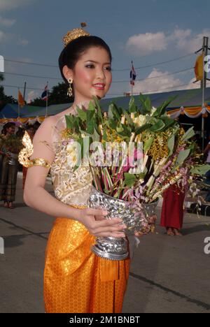 Pretty woman on traditional dress holding flower on parade in Tak Bat Dok Mai Festival is Ceremony of Wat Phra Buddhabat Woramahaviharn temple in Thai. Stock Photo