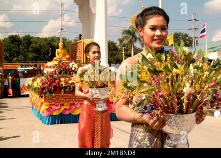 Pretty woman on traditional dress holding flower on parade in Tak Bat Dok Mai Festival is Ceremony of Wat Phra Buddhabat Woramahaviharn temple in Thai. Stock Photo