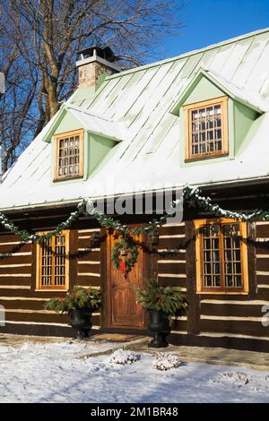 Old 1800s two story Canadiana cottage style log home with Christmas decorations in winter. Stock Photo