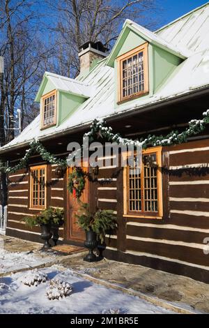 Old 1800s two story Canadiana cottage style log home with Christmas decorations in winter. Stock Photo