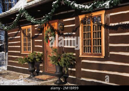 Old 1800s two story Canadiana cottage style log home with Christmas decorations in winter. Stock Photo