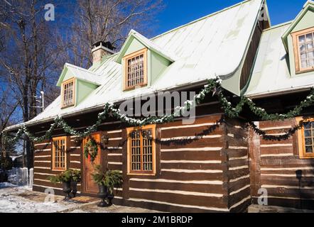 Old 1800s two story Canadiana cottage style log home with Christmas decorations in winter. Stock Photo