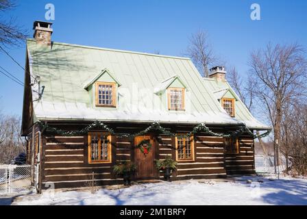 Old 1800s two story Canadiana cottage style log home with Christmas decorations in winter. Stock Photo