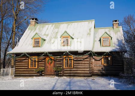 Old 1800s two story Canadiana cottage style log home with Christmas decorations in winter. Stock Photo