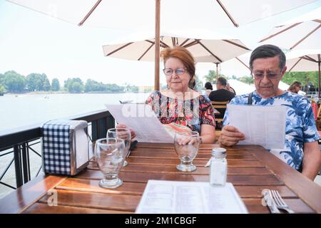 Senior latin couple reading the menu for lunch at an outdoor table during the summer. Stock Photo