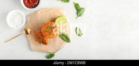 Tasty lentil cutlets and sauce on light background with space for text Stock Photo