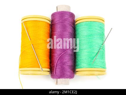 Colorful thread spools with needles on white background Stock Photo