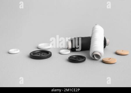 Thread spools with buttons on grey background Stock Photo