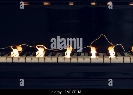 Glowing Christmas lights on piano keys, closeup Stock Photo