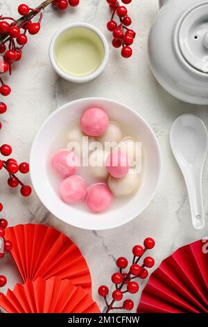 Bowl of tangyuan, cup, teapot and Chinese decor on light background ...