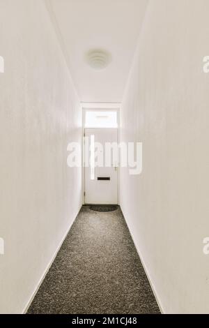 Interior of modern flat in minimal style with narrow empty corridor illuminated by lamps Stock Photo