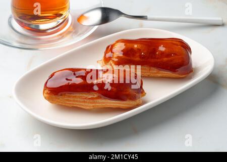 Two caramel eclairs on a white plate Stock Photo