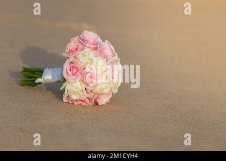 A large bouquet of roses is placed on the sandy beach. looks fresh and beautiful golden sunlight shining through Stock Photo