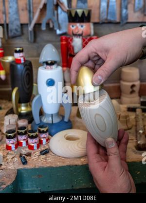 PRODUCTION - 08 December 2022, Saxony, Seiffen: In his workshop in Seiffen, wooden toy maker Markus Füchtner shows turned components for a new smoking rocket in which high-tech material from space travel is used. Scientists from the Fraunhofer Institute for Machine Tools and Forming Technology worked with the team led by wooden toy maker Markus Füchtner for six months. Now, during Advent, they are raising the curtain on the prototype of their smoking rocket. The warmth of an incense candle opens the tip of the rocket as if by magic and a mini nutcracker peeps out. The secret behind it is a spr Stock Photo