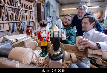 PRODUCTION - 08 December 2022, Saxony, Seiffen: Wooden toy maker Markus Füchtner (l-r) presents a new smoking rocket in his workshop in Seiffen together with partners Wolfgang Braun from the 'Denkstatt Erzgebirge' and Holger Kunze from Fraunhofer IWU, in which high-tech material from space travel is built in. Scientists from the Fraunhofer Institute for Machine Tools and Forming Technology worked for six months with the team led by wooden toy maker Markus Füchtner. Now, during Advent, they are raising the curtain on the prototype of their smoking rocket. The warmth of an incense candle opens t Stock Photo