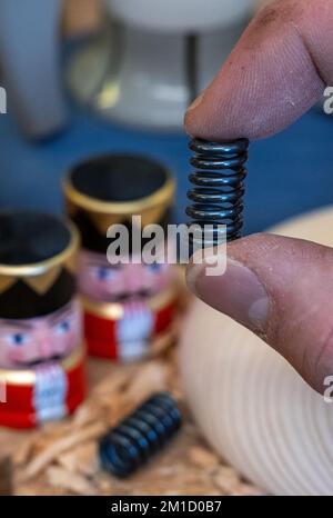 PRODUCTION - 08 December 2022, Saxony, Seiffen: Wooden toy maker Markus Füchtner demonstrates a special spring made of high-tech material like that used in space travel in his workshop in Seiffen. Scientists from the Fraunhofer Institute for Machine Tools and Forming Technology spent six months working with the team led by wooden toy maker Markus Füchtner. Now, during Advent, they are raising the curtain on the prototype of their smoking rocket. The warmth of an incense candle opens the tip of the rocket as if by magic and a mini nutcracker peeps out. The secret behind it is a spring that expa Stock Photo