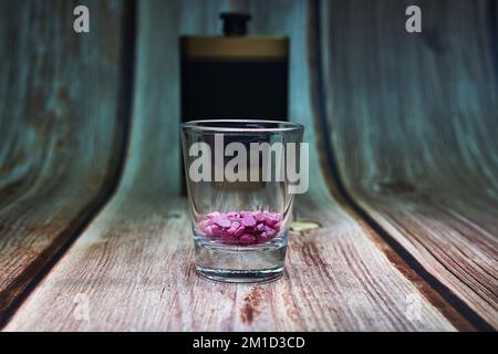 flask and shot glass with decorated purple rocks on wood Stock Photo
