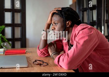 Upset young african guy remote worker coping with freelance burnout, sitting at desk with laptop Stock Photo