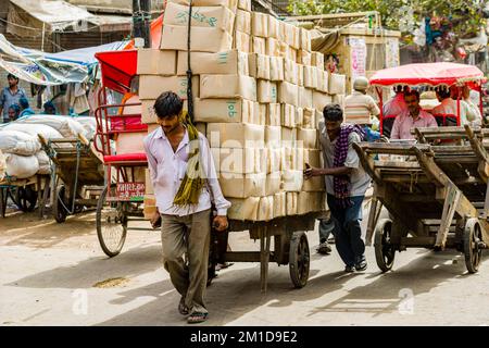 Goods and big loads get transported by human power on carts and cycle rickshaws on Khari Baoli Road in Old Delhi Stock Photo