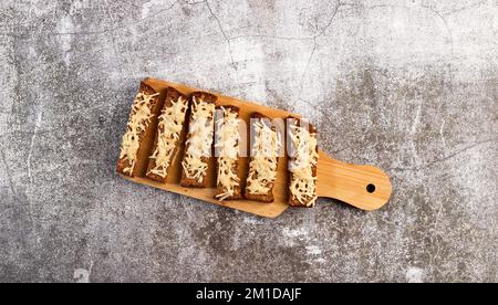 Rye bread croutons with cheese on a wooden cutting board on a dark grey background. Top view, flat lay Stock Photo