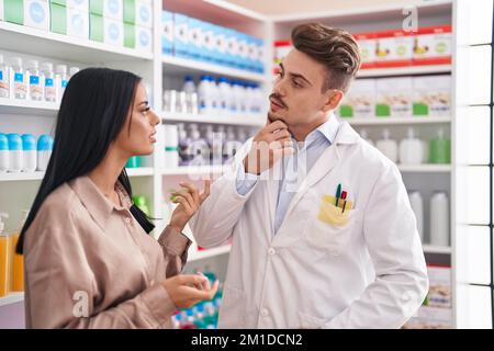 Man and woman pharmacist and client speaking at pharmacy Stock Photo