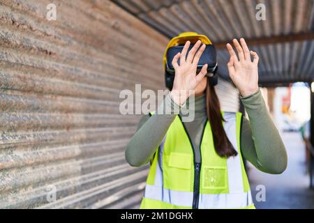 Young beautiful hispanic woman architect using virtual reality glasses at street Stock Photo