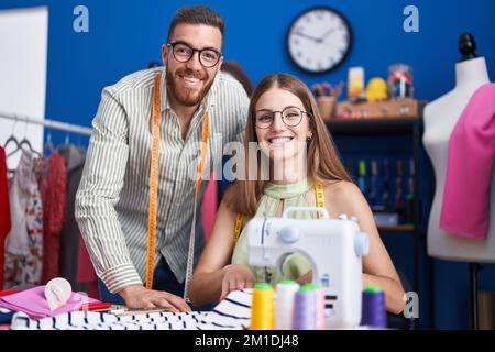 Man and woman tailors smiling confident using sewing machine at clothing factory Stock Photo