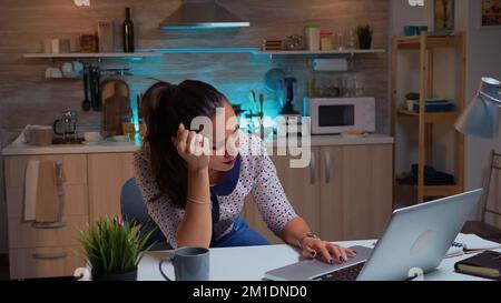 Woman closing eyes because of exhaustion while working on a project for work late at night. Busy exhausted remote employee napping on chair waking up reading on laptop using modern technology network Stock Photo