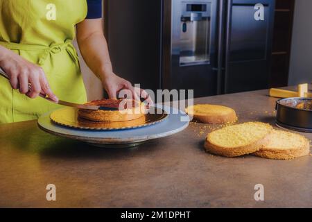 Unrecognisable woman spreding homemade jam on a delicious sponge cake. DIY, sequence, step by step, part of series. Stock Photo