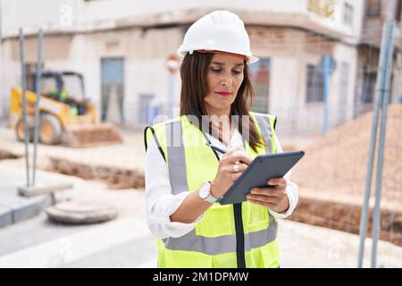 Young beautiful hispanic woman architect drawing on touchpad with relaxed expression at street Stock Photo