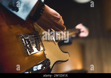 Closeup of electric guitar. Hands of unrecognizable caucasian person using electric guitar. Indoor shot. Blurred background. High quality photo Stock Photo