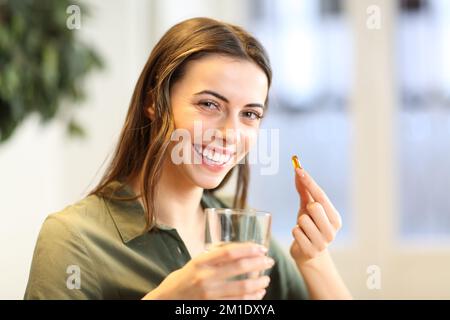 Happy woman showing vitamin pill ready to take it at home Stock Photo