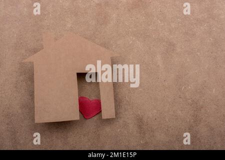 Little house shape cut out of paper and a heart on a canvas background Stock Photo
