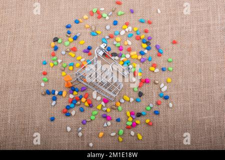 Little trolley amid Colorful pebbles on canvas background Stock Photo