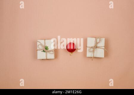Christmas background with two gift boxes wrapping in craft paper and red baubles, pine branch on beige background with empty space. Greeting card,  wi Stock Photo