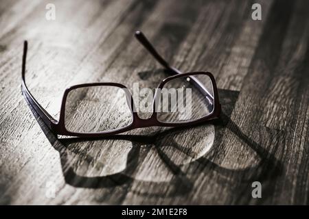 Old glasses on wooden table surface closeup, light and shadows Stock Photo