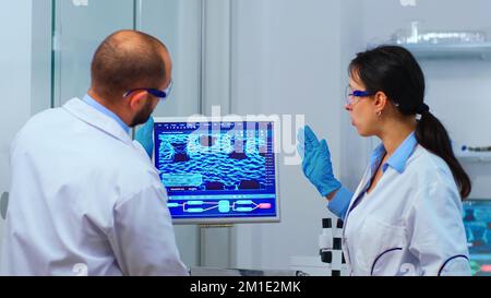 Scientists coworkers working in chemical modern equipped laboratory. Multiethnic stuff examining vaccine evolution using high tech and technology researching treatment against covid19 virus Stock Photo