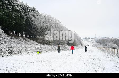 Brighton UK 12th December 2022 - Walkers out in the snow near Brighton Racecourse this morning as the freezing weather is forecast to last for the next few days throughout Britain . : Credit Simon Dack / Alamy Live News Stock Photo