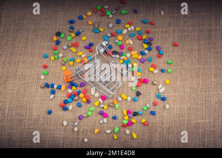Little trolley amid Colorful pebbles on canvas background Stock Photo
