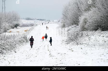 Brighton UK 12th December 2022 - Walkers out in the snow near Brighton Racecourse this morning as the freezing weather is forecast to last for the next few days throughout Britain . : Credit Simon Dack / Alamy Live News Stock Photo