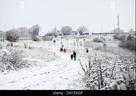 Brighton UK 12th December 2022 - Walkers out in the snow near Brighton Racecourse this morning as the freezing weather is forecast to last for the next few days throughout Britain . : Credit Simon Dack / Alamy Live News Stock Photo